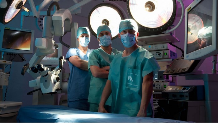 Three surgeons in operating room with medical equipment
