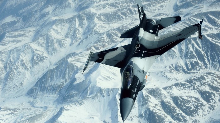 F-16 Fighting Falcon flying over snowy mountains