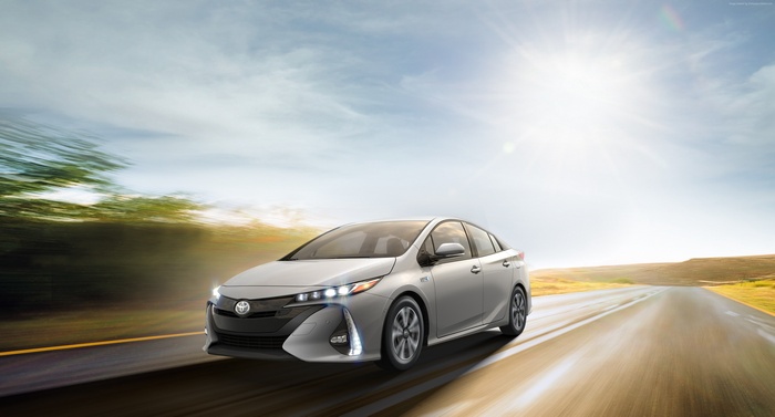 Silver Toyota Prius Prime driving on a sunny road