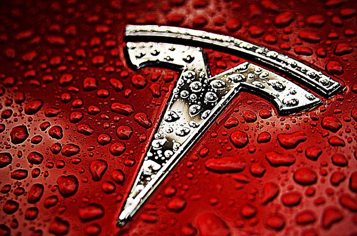 Tesla logo on a red surface with water droplets