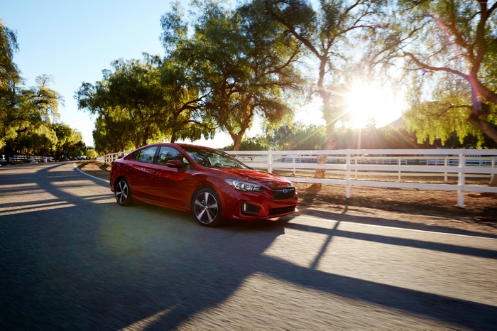 Red Subaru Impreza Sedan driving on a road