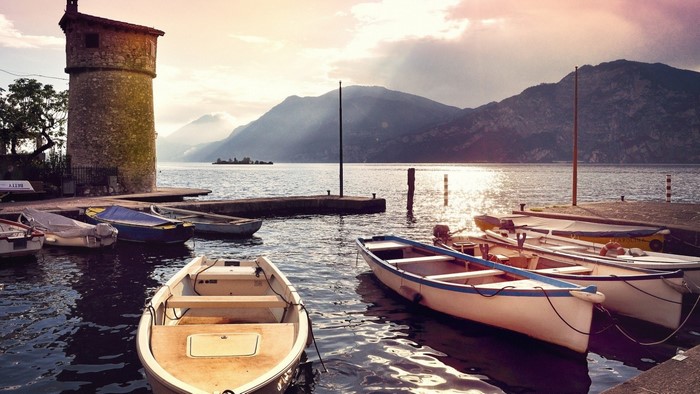 Boats docked by a tower on a lake at sunset