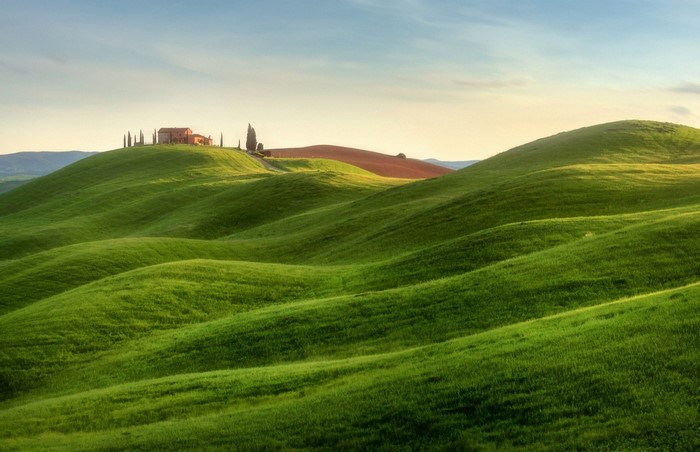 Tuscan landscape with rolling green hills and a farmhouse