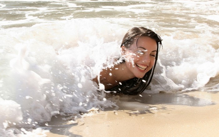 Woman laughing in ocean waves at the beach