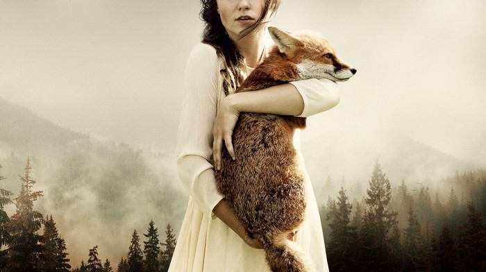 Woman holding a fox in a misty forest