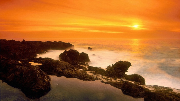 Sunset over rocky coastline with ocean waves