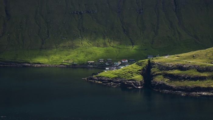 Village on a green cliff overlooking a dark body of water