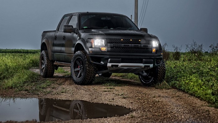 Black Ford Raptor pickup truck on a dirt road