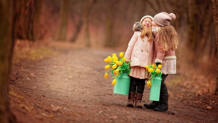Two girls with yellow tulips in a forest