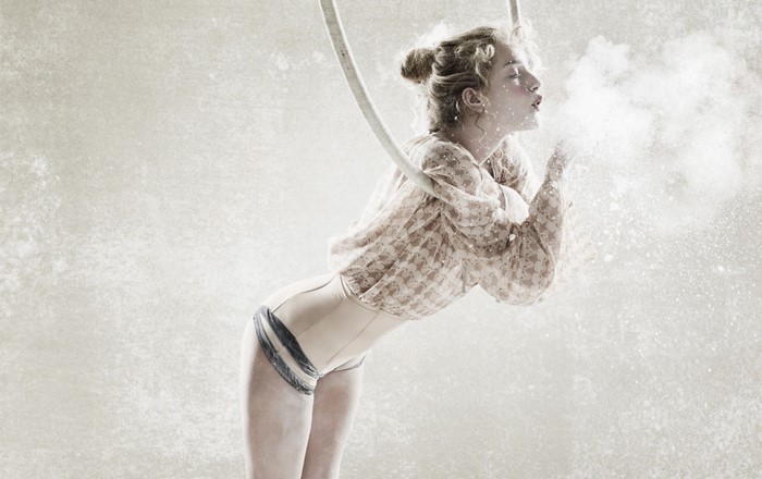 Woman blowing powder while hanging from a rope