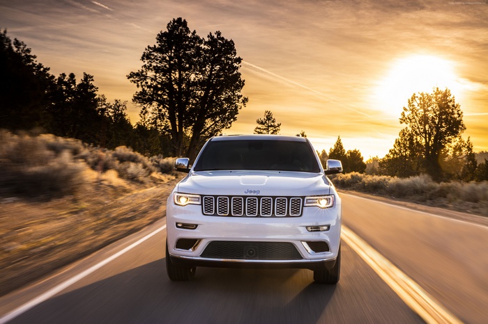 White Jeep Grand Cherokee Summit driving at sunset