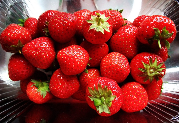 A pile of fresh strawberries in a clear container