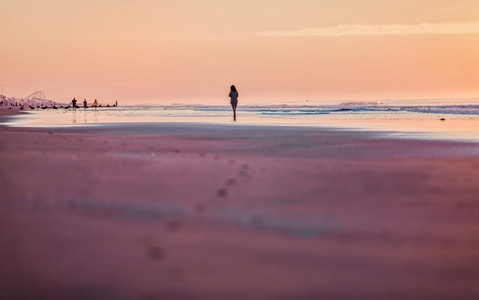 Woman walking on beach at sunset