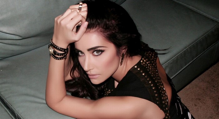 Woman with dark hair and makeup posing on a couch