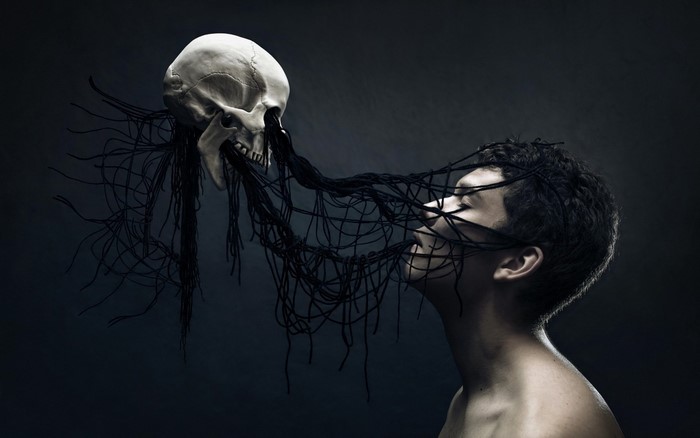 Man entangled by dark threads from a skull