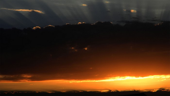 Sunlight rays through dark clouds at sunset