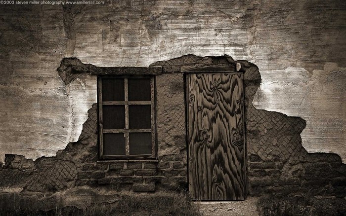 Dilapidated wall with a window and a wooden door