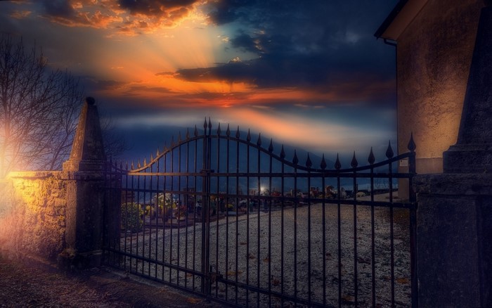 Cemetery gates at sunset with sun rays