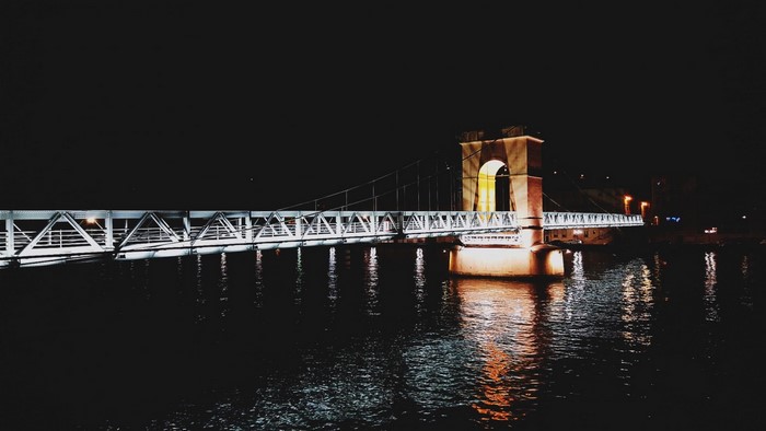 Illuminated bridge over water at night