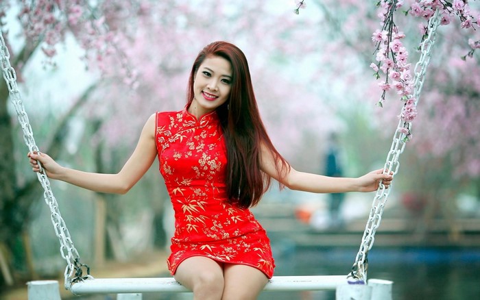 Woman in red dress on a swing with cherry blossoms