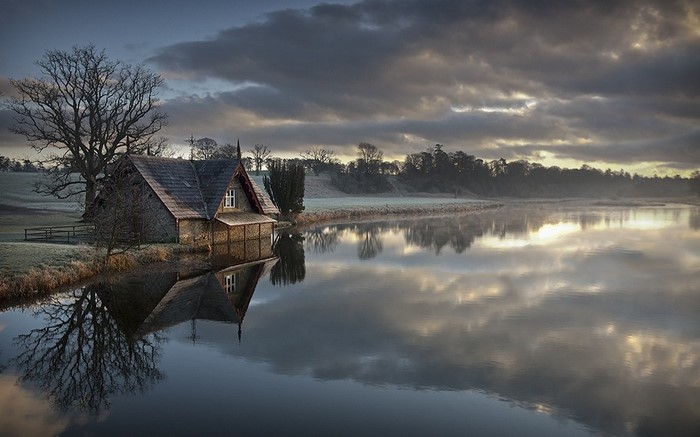 Stone boathouse on a misty lake at sunrise