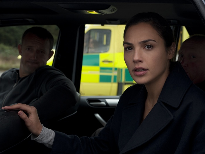 Gal Gadot in a car with an ambulance in the background