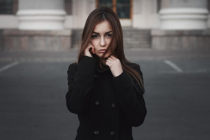 Young woman in black coat posing outdoors