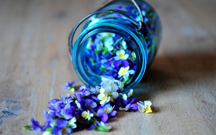 Blue glass jar with purple and white flowers spilling out