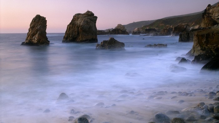 Rocky coast with misty ocean waves at sunrise