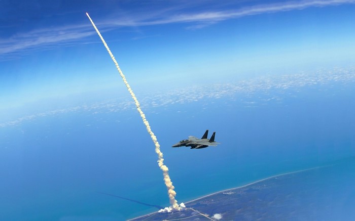 F-15 Eagle flies alongside a rocket launch
