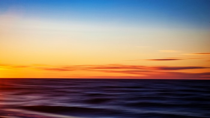 Blurred ocean waves at sunset with colorful sky