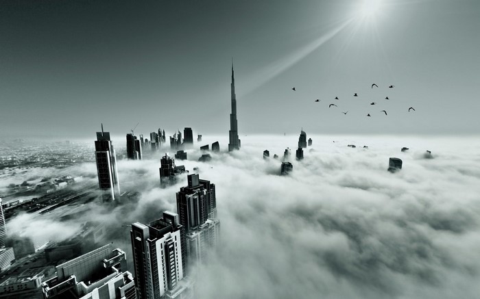 Dubai skyscrapers emerging from clouds with sun rays and birds