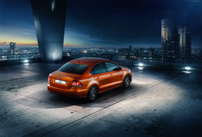 Orange Volkswagen Polo Sedan on rooftop at night