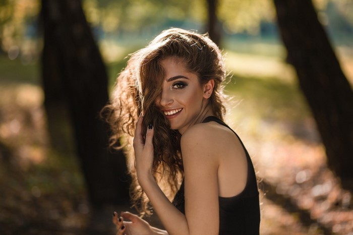 Woman with curly brown hair smiling in sunlight