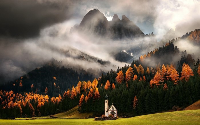 Church in misty mountains with autumn trees