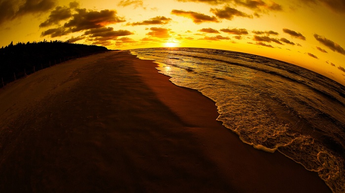 Sunset over a beach with waves and clouds