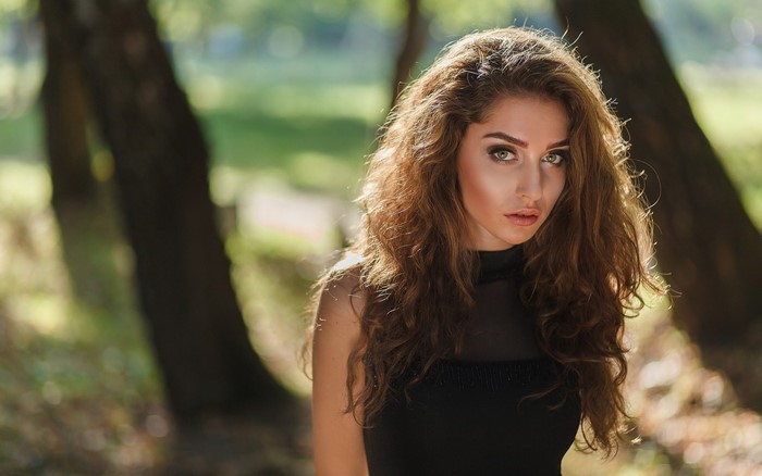 Woman with long wavy brown hair in a black dress outdoors