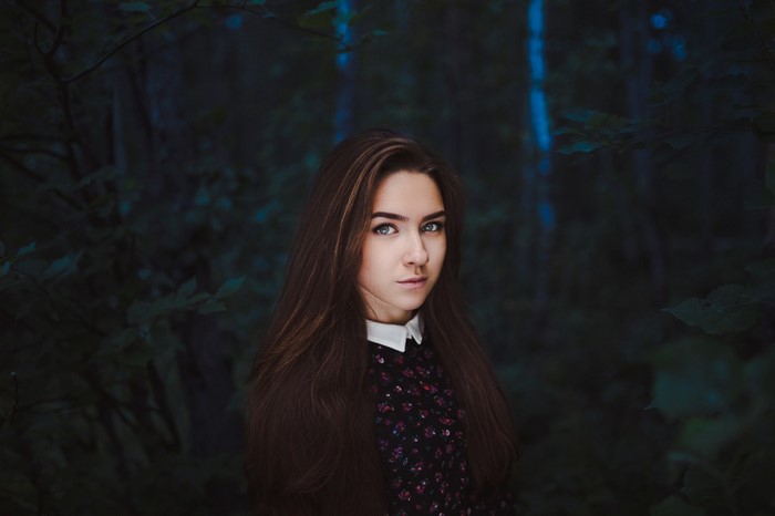 Young woman with long brown hair in a dark forest
