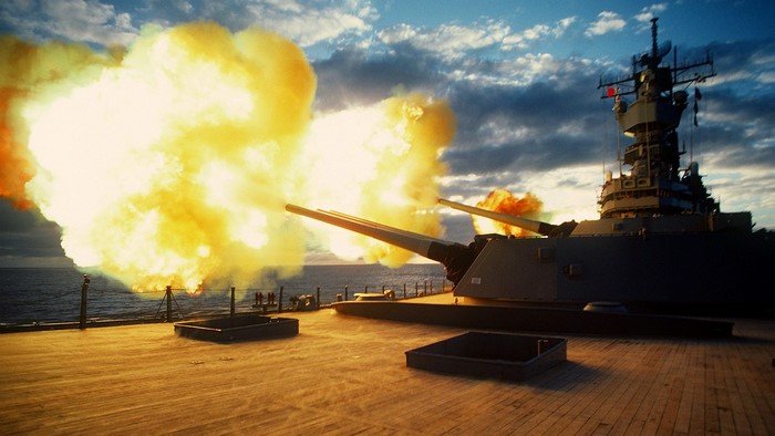 Battleship firing its main guns with large explosions