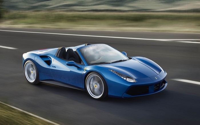 Blue Ferrari 488 Spider driving on a road