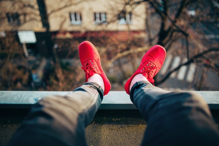 Person wearing red shoes sitting on a rooftop