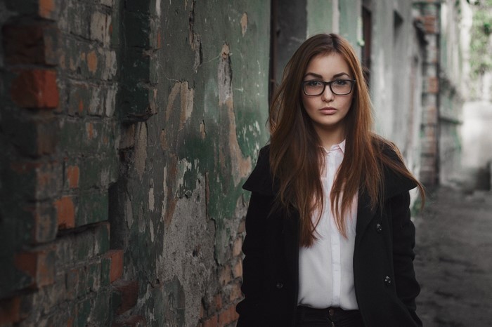 Woman with glasses standing in front of a brick wall