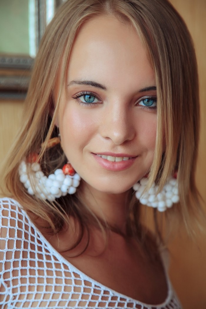 Young woman with blonde hair and blue eyes wearing large earrings