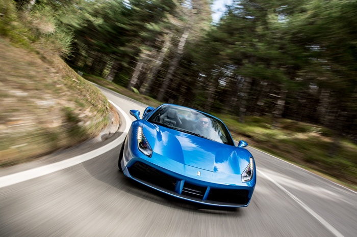 Blue Ferrari 488 Spider driving on a winding road