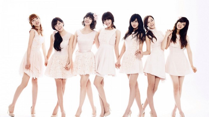Seven young women in light pink dresses posing together