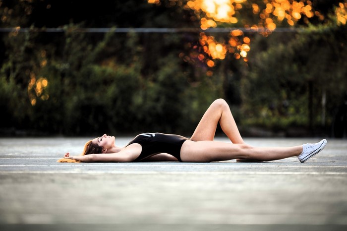 Woman in swimsuit lying on tennis court