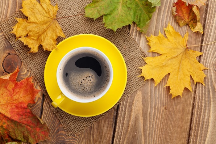 Cup of coffee with autumn maple leaves on a wooden table