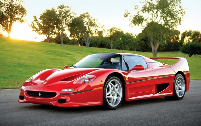 Red Ferrari F50 sports car on a road with trees