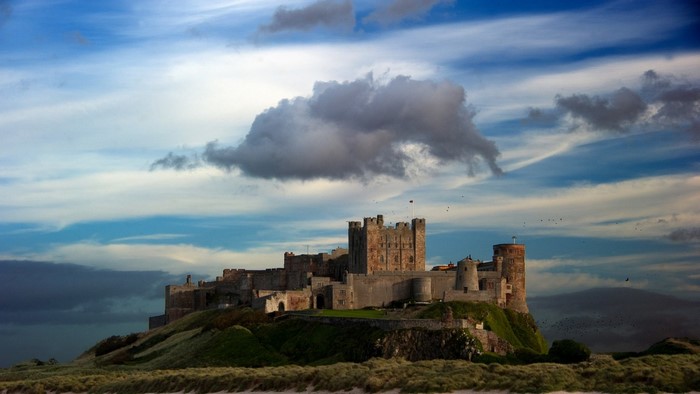 Bamburgh Castle on a hill under a cloudy sky