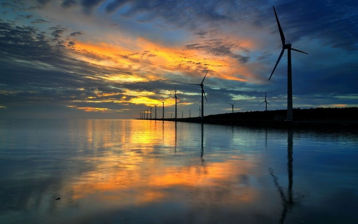 Wind turbines at sunset reflected in the sea